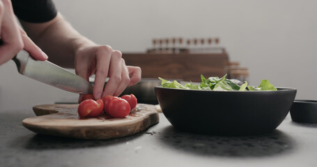 man cut cherry tomato for salad on kitchen countertop