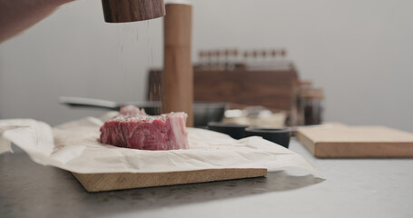 man grinding pepper on new york steak on countertop