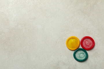 Multicolored condoms on white textured background, space for text