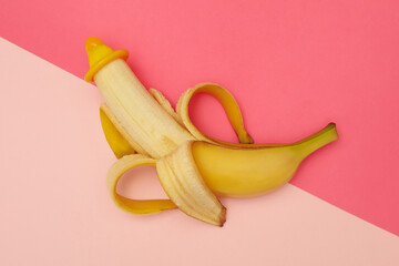 Banana with condom on two tone background