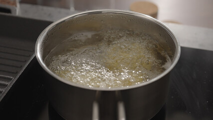 fettuccine boiling in saucepan with back light