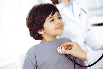 Doctor-woman examining a child patient by stethoscope. Cute arab boy at physician appointment. Medicine concept