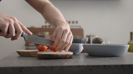 man cut cherry tomato for salad on kitchen countertop