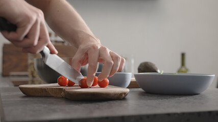 man cut cherry tomato for salad on kitchen countertop