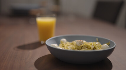 pesto fettuccine with mozzarella in blue bowl on walnut table