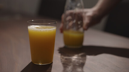 pour orange juice in tumbler glass on walnut table with copy space