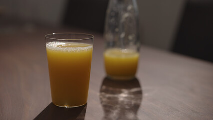 orange juice in tumbler glass on walnut table with copy space
