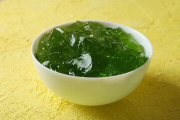 Bowl of kiwi jelly on yellow textured background