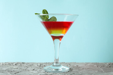 Cocktail glass with strawberry and orange jelly on blue background