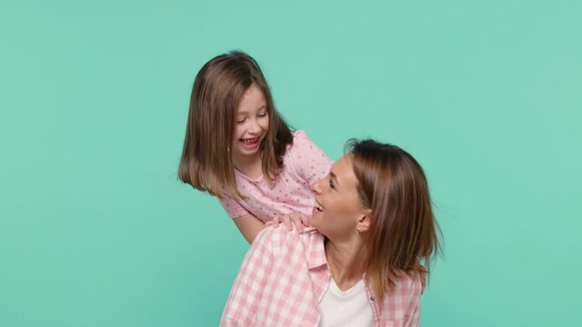 Happy woman in pink clothes have fun with cute child baby girl 5-6 years old. Mommy little kid daughter stand behind hug kiss isolated on pastel blue background studio Mother's Day love family concept