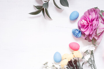 Easter composition of flowers and Easter eggs on a white wooden background.