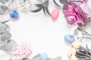Easter composition of flowers and Easter eggs on a white wooden background.