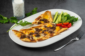 Sliced ​​cubed meat pita with buttermilk and salad on stone table.