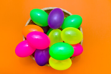 Wicker basket with colorful Easter eggs on yellow background.Top view.