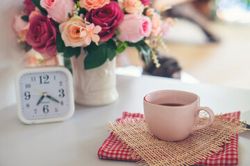 Coffee Break Time. A cup of coffee, Rose Flower vase, and clock place on white home office.