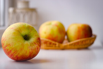 A few ripe apples on a white surface. Rear background is blurred