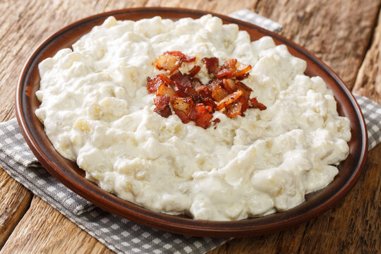 Bryndzove halusky or sheep cheese dumplings are a Slovak national dish prepared from potatoes, sheep cheese and bacon closeup in the plate on the table. horizontal