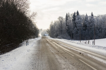 Winter road in snowy forest on a cold day.