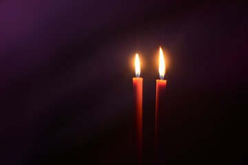 Burning candles at Night. Two red candles on dark purple background.