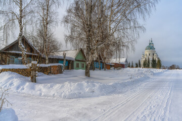 Rural winter landscape with wooden houses, a rasp of firewood, tall birches and a snowy road...