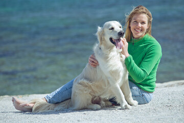Cheerful pretty young woman hugs her dog on the beach. High quality photo.