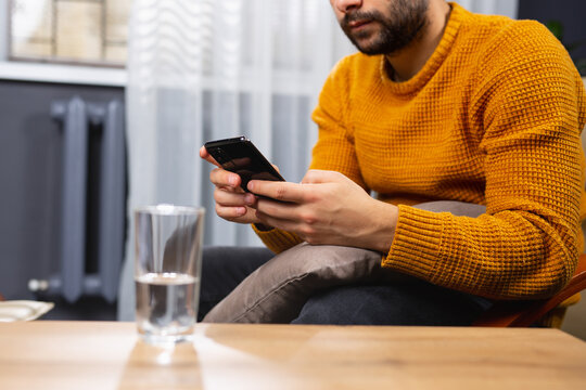 Cropped Photo Of A Beard Adult Man, Dependent Of Virtual World. Online Psychotherapy Session, A Glass Of Water On The Table. A Businessman Is Looking For A New Job After Bankruptcy.