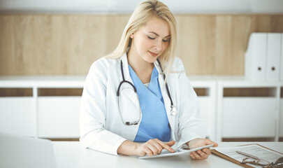 Woman-doctor standing in hospital or clinic and using tablet pc. Data and best service in medicine and healthcare
