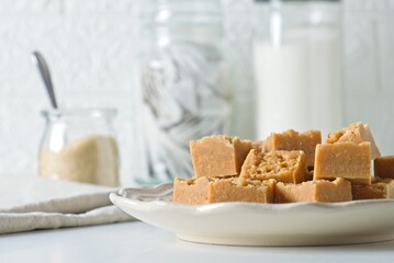 Homemade fudge cut into cubes on plate on white kitchen counter