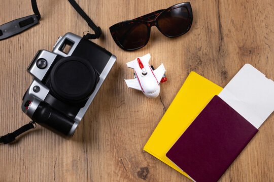 Tourist concept, background of a wooden table with necessary documents prepared for the trip, sunglasses and a photo camera. Safe pandemic travel.