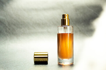 An open bottle of a golden perfume with the top placed on the side. Seamless grey and white...