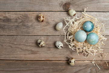 Easter background with Easter eggs in a nest on a wooden table. Top view with copy space. 