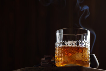 Glass of whiskey with chocolate in a smoke bar.