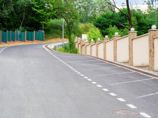 A road leading upward with a fence on both sides and green trees along