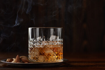 Glass of whiskey with cashew and almond in a smoke bar.