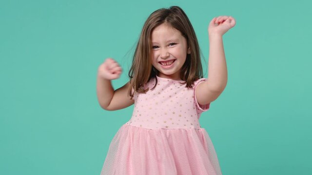 Little toothy smiling cheery cute kid girl 5-6 years old wears pink dress have fun dancing isolated on pastel blue background child studio portrait. Mother's Day love family people lifestyle concept