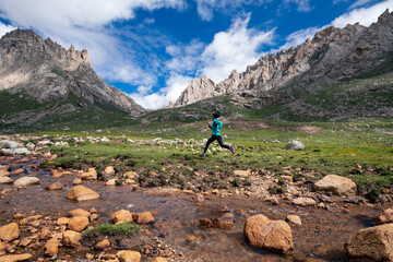 Woman trail runner running in wild mountains