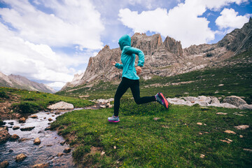 Woman trail runner running in wild mountains