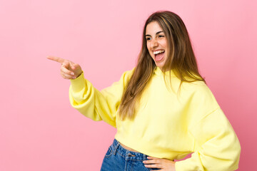 Young woman over isolated pink background pointing finger to the side and presenting a product