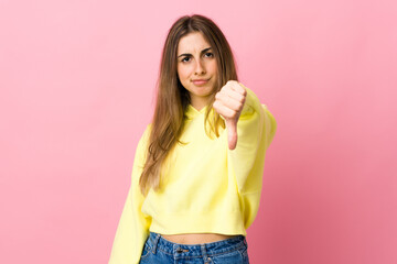 Young woman over isolated pink background showing thumb down with negative expression