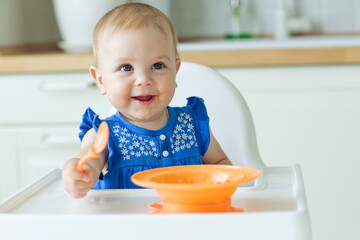 A small child in a high chair feeds himself. High quality photo.