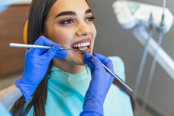 Woman looks in the mirror in dentist chair. Patient's teeth shade with samples for bleaching treatment. oral hygiene. Woman at the dentist. Child in the dental chair dental treatment during surgery.
