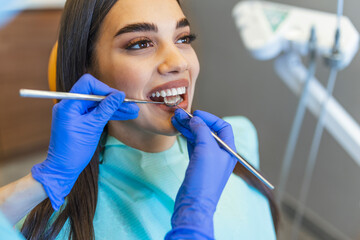 Woman looks in the mirror in dentist chair. Patient's teeth shade with samples for bleaching...