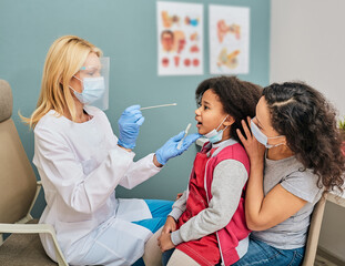 Little girl with her parent during PCR test of Covid-19 in a medical clinic. Oral swab for...