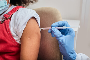 Cropped of little girl's shoulder while vaccine injection in a medical clinic. Global pandemic