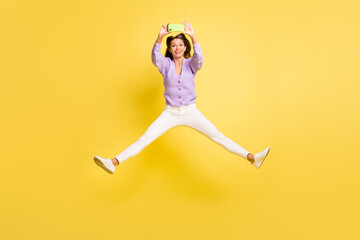 Full body photo of young cheerful girl happy smile jump up shoot selfie smartphone isolated over yellow color background