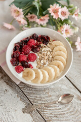 Yogurt bowl with sliced bananas, raspberry and cranberry fruits. Oatmeal with fruits.