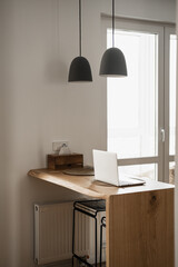 Aesthetic minimal home, living room interior design. Hanging lamps, wooden stand with laptop computer. Home office desk workspace. Blog, web, social media concept. Work at home.