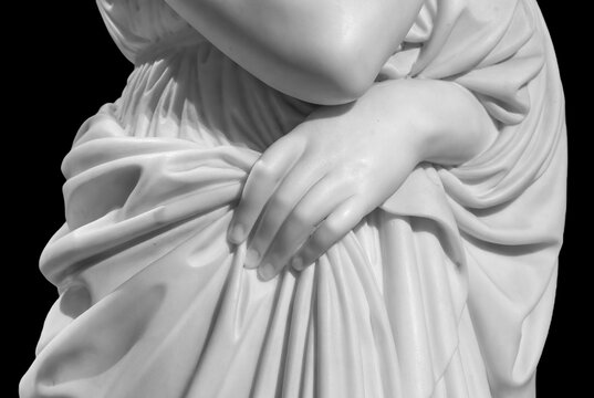 Closeup of white stone marble statue woman hand holding a tunic isolated on black background