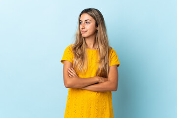 Young hispanic woman over isolated blue background looking to the side