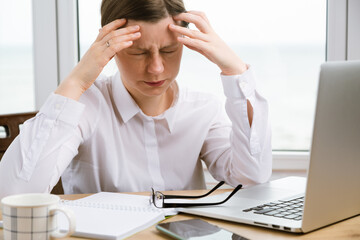 A young woman got a headache at work. Finance problems, crisis coming. An exhausted student with glasses doing research at home.